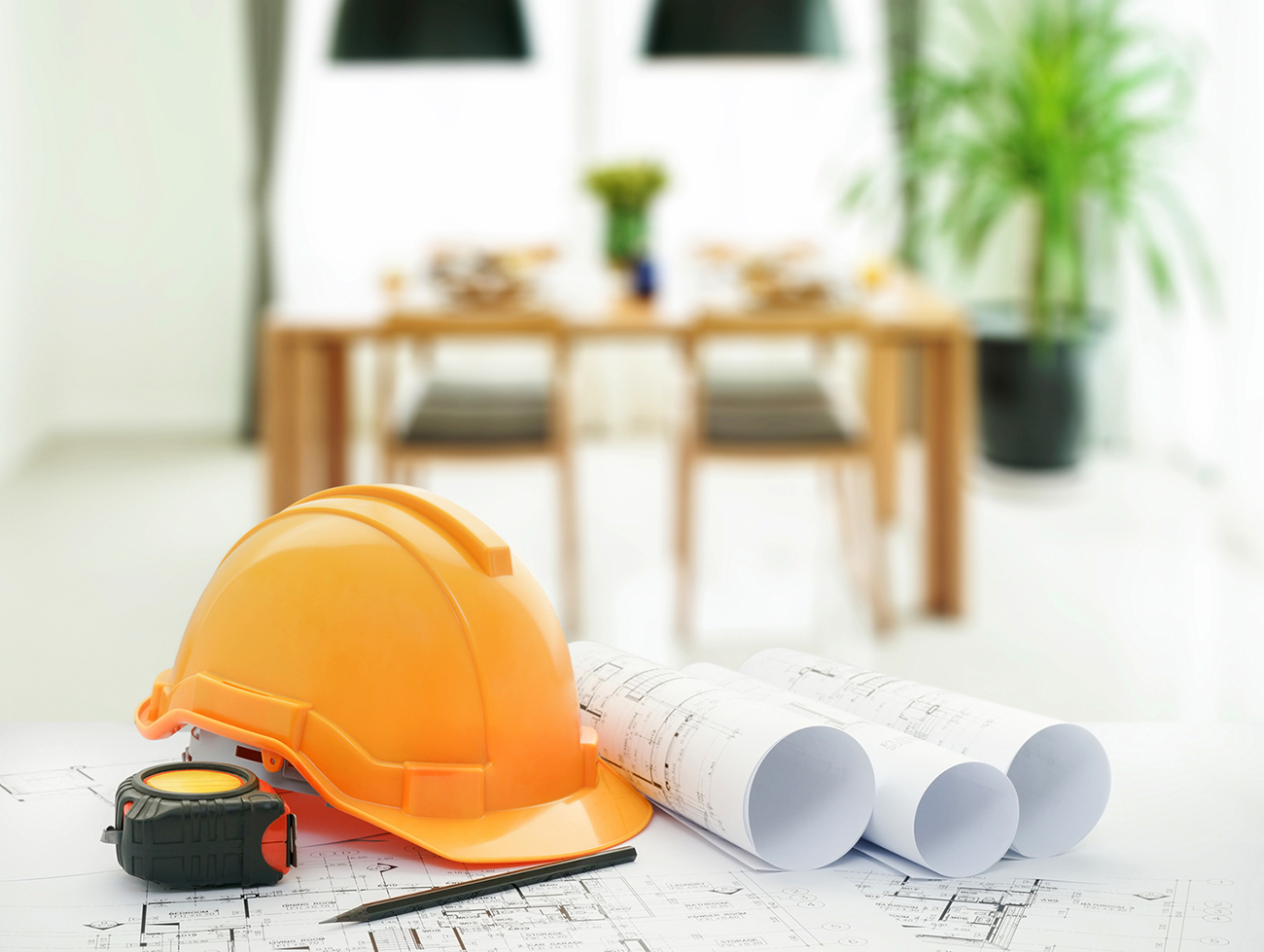 A Civil engineer's architectural blueprints with safety helmet and tools with home Interior background  