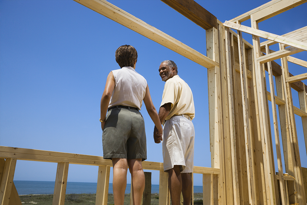 Couple holding hands at the construction site of their new beach house after home inspection services were preformed 